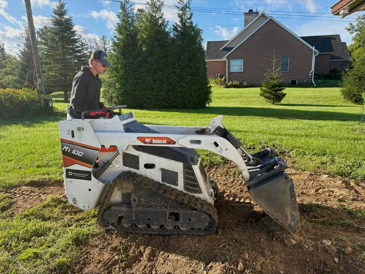 Ziegler Construction crew member operating a compact track loader to grade a dirt lot